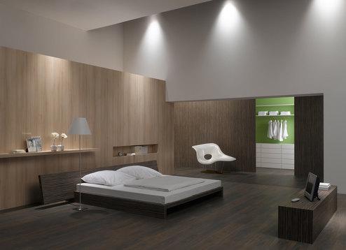 Schlafzimmerimpression mit Holzverkleidung an Wand Schlafzimmerimpression von Bett, Nachtisch und Sideboard mit Holzverkleidung an Wand und indirektert Beleuchtung