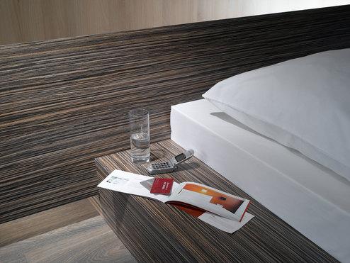 Detailaufnahme von Bettumrandung Detailaufnahme von Bettumrandung in dunklem Holz mit Ablagemöglichkeit